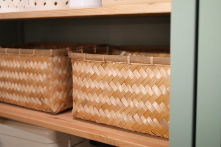 Woven storage baskets on wooden shelf in a modern kitchenの写真素材