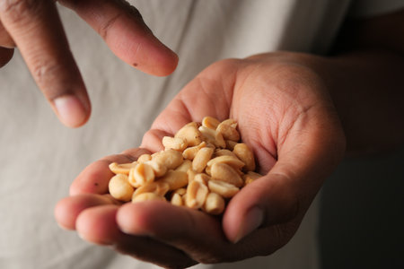 Holding peanuts in a hand while pointing at a snackの写真素材