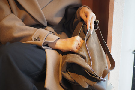 Woman reaching into a stylish bag at a cozy locationの写真素材