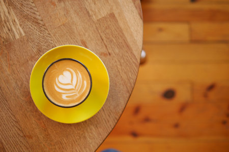 Warm latte art served on a cozy wooden tableの写真素材