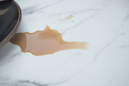 Coffee spill on marble surface near a plateの写真素材