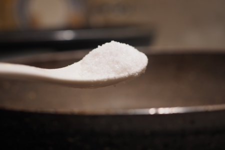 Measuring salt for cooking in a kitchen settingの写真素材