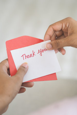 Hands holding a thank you card with a red envelopeの写真素材