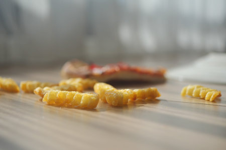 Crispy fries spilled on wooden floor in sunlightの写真素材