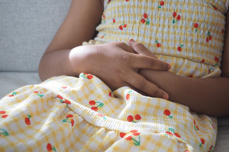 Child suffering stomach pain sitting on a sofaの写真素材