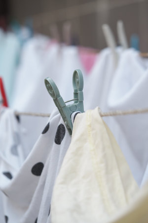 Clothespin holding wet fabric on a clothesline in the sunの写真素材