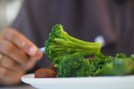 Fresh broccoli and greens enjoyed at a sunny mealの写真素材