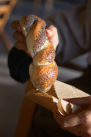 Hand holding freshly baked twist bread in a cozy cafeの写真素材