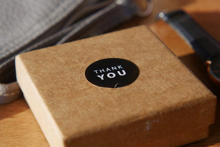 Thoughtful gift box with thank you sticker on wooden tableの写真素材