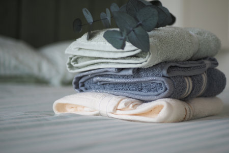 Soft towels stacked neatly on a bed with greeneryの写真素材