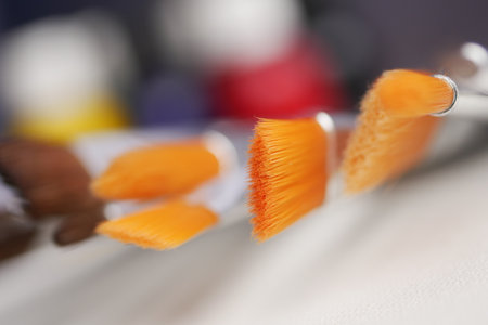 Bright orange paint brushes on a clean workspace surfaceの写真素材