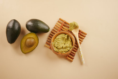 Creamy avocado spread on bamboo mat with whole fruitsの写真素材