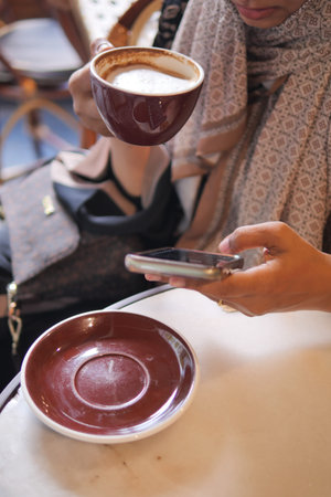 Enjoying coffee while using a smartphone in a cafe