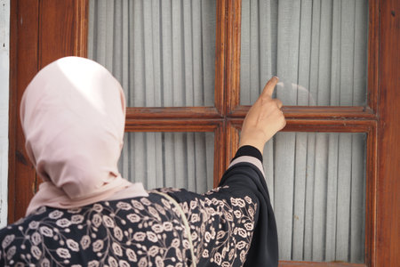 Woman knocking on a wooden door in a quiet neighborhoodの写真素材
