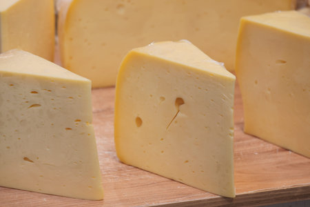 Cheese on a wooden board cut into triangular pieces
