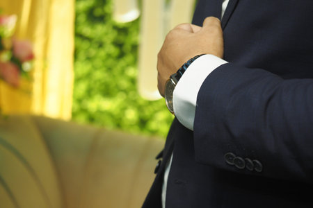 Man in suit adjusting sleeve in elegant settingの写真素材