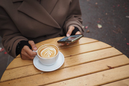 Enjoying coffee while using a smartphone at a cozy cafe