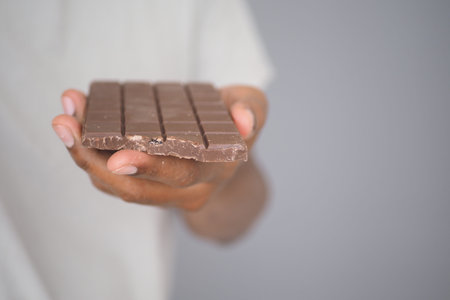 Holding a piece of chocolate bar against a gray background