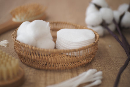 Cotton pads and cotton balls in a wicker basket on a tableの写真素材