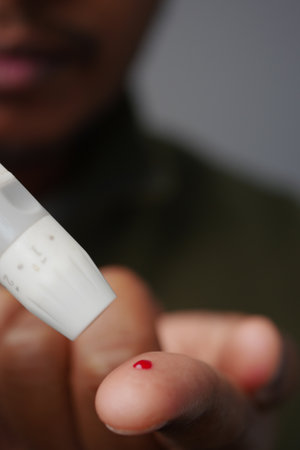 A person shows a finger with a drop of red liquid on itの写真素材