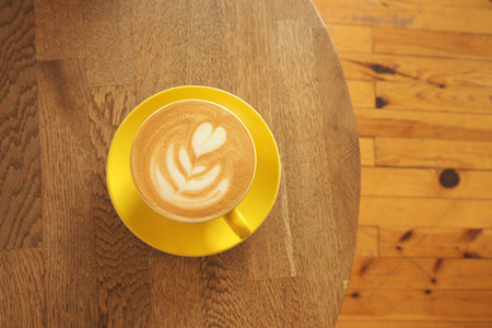 Coffee served on a yellow cup on a wooden tableの写真素材