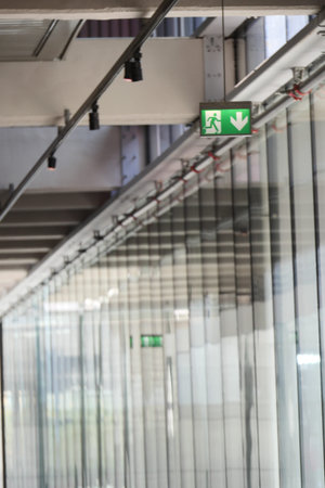 Exit signs above a clear glass corridor in a buildingの写真素材