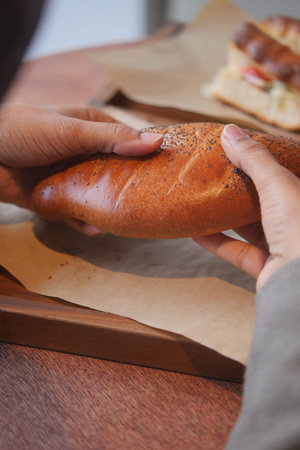 Hands hold a fresh bread on a wooden tray
