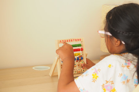 Child plays with counting beads at a table in the room