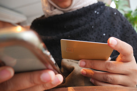 Person using a smartphone and holding a card in a cafe
