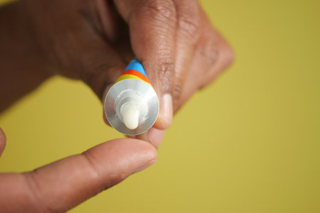 Person applies cream from tube in indoor settingの写真素材