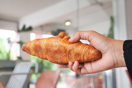 Enjoying a fresh croissant in a cafe settingの写真素材