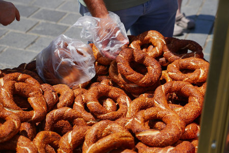 Hands reach for fresh turkish simit bagels at a market in daytime