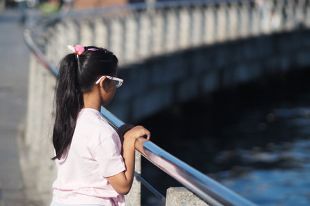 Girl standing by railing near water in the cityの写真素材