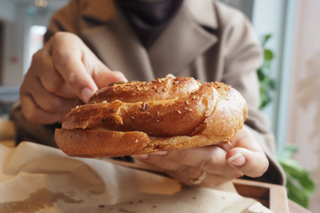 Holding a baked bread roll in a cozy cafe setting