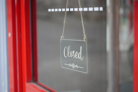 Closed sign hangs on shop window in busy street areaの写真素材