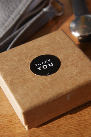 Gift box with thank you sticker on wooden table