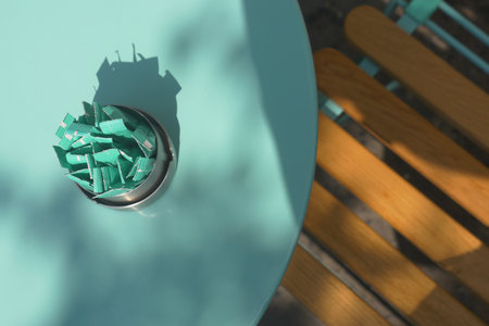 Sugar packets on a blue table with wooden chairsの写真素材