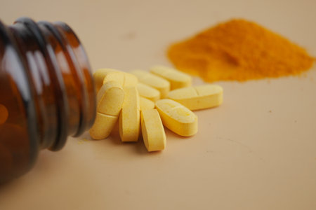 Yellow pills and turmeric powder on a plain surfaceの写真素材