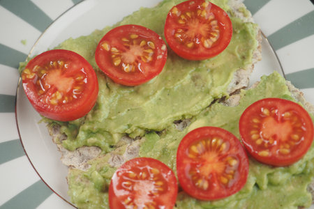 Toast with avocado and sliced tomatoes on a plateの写真素材