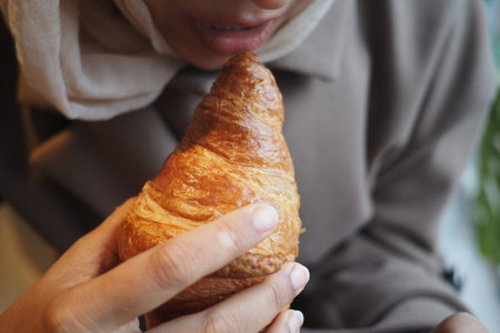 Enjoying a croissant in a cafe during the morning rushの写真素材