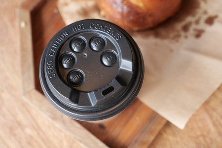 Coffee cup on a wooden table with baked goods nearbyの写真素材