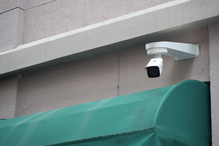 Security camera monitors entrance near green awningの写真素材