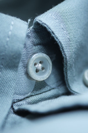 Close view of a button on a gray fabric shirt