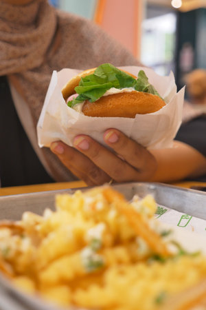 Hand holding food with fries on a tray