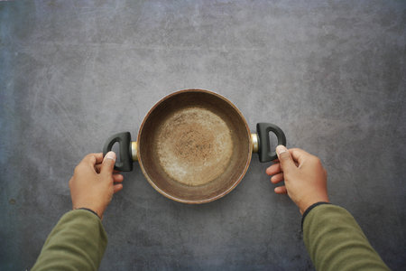 Hands holding a cooking pot on a gray surfaceの写真素材
