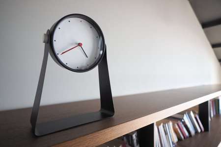 Stylish clock on shelf in modern interior space