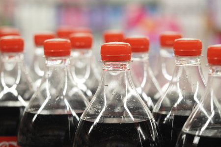 Bottles of soda lined up on a store shelf with orange caps