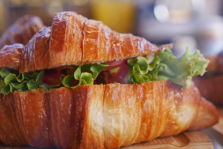 Croissant filled with lettuce and tomato on a wooden plateの写真素材