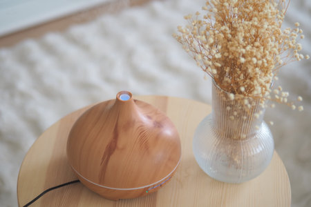 Wooden diffuser and dry flowers on a small table in a roomの写真素材