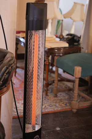 Floor heater stands in a room with table and chairsの写真素材